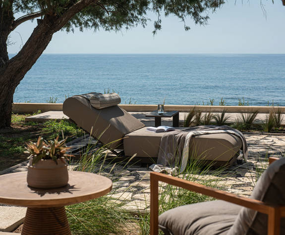 The Echo Of The Sea Beachfront Villa chair, small round table, sunbed and sea view