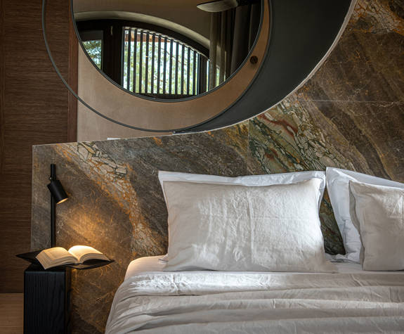 The Echo Of The Sea Beachfront Villa double bed close-up and bedside table with an open book on it