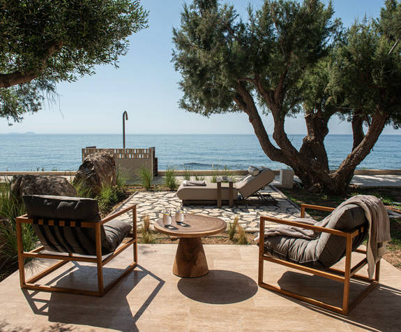 The Echo Of The Sea Beachfront Villa terrace with two chairs, a decorated small round table, sunbeds and sea view