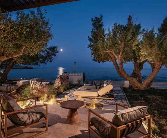 The Echo Of The Sea Beachfront Villa terrace with sunbeds, chairs and sea view at night