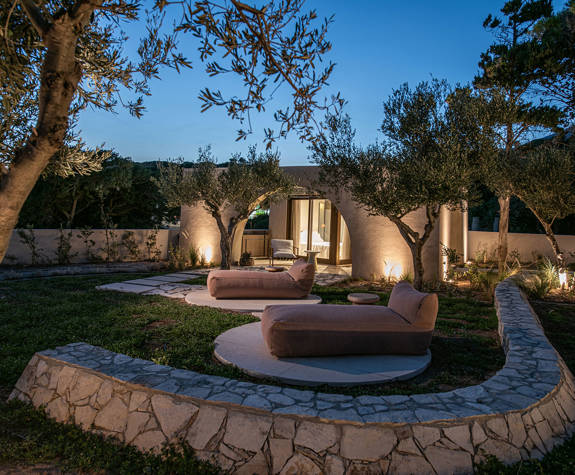 The Echo Of The Sea Beachfront Villa garden with sunbeds lit up at dusk